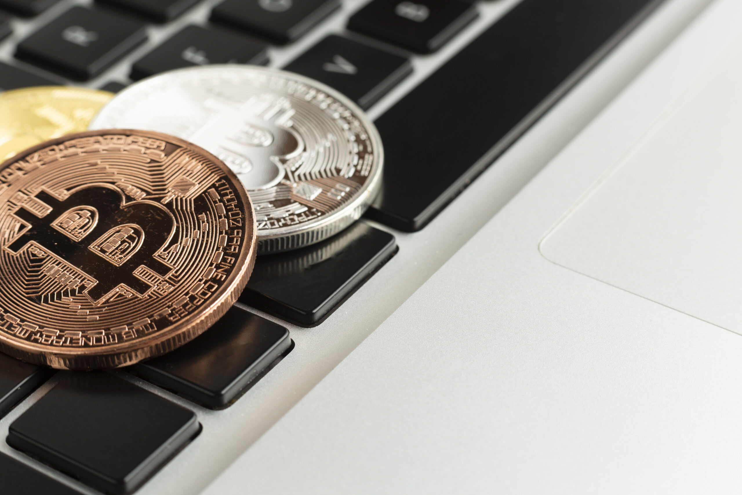 Bitcoin coin resting on a laptop keyboard, symbolizing the integration of Bitcoin with modern DeFi platforms and digital investment tools.
