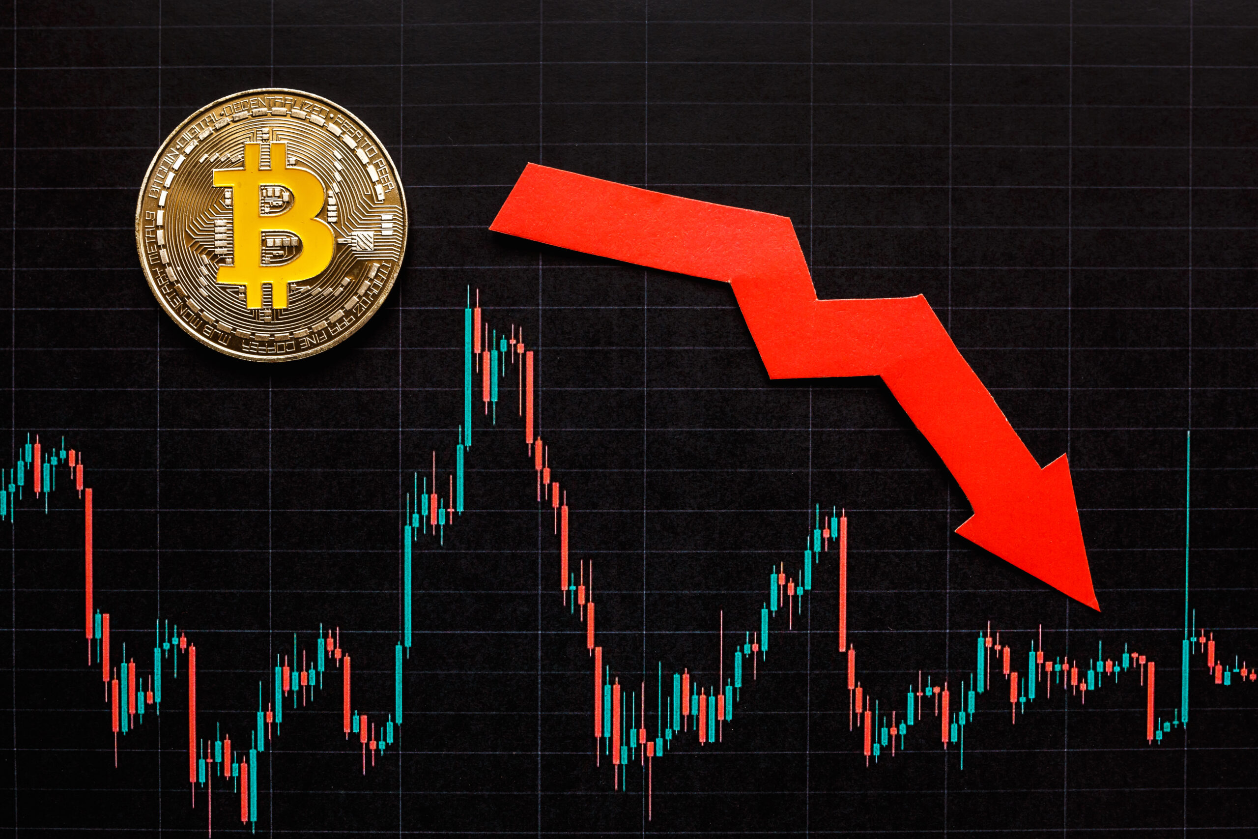 Bitcoin with a red downward arrow and a market chart, representing investment pause and economic volatility